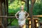 A blonde in tight beige dress stands by the gazebo in the forest