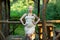 A blonde in tight beige dress stands by the gazebo in the forest