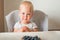 Blonde toddler boy eating Yummy blueberries on highchair close-up and copy space