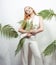 Blonde Total White look. Fashionable model photo posing. Woman in tropical leaves party all in white. The concept of fashion,