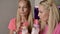 The blonde twin sisters drink a milkshake from a glass with tubes.