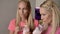 The blonde twin sisters drink a milkshake from a glass with tubes.