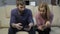 Blonde wife and husband sitting on sofa uses smartphones and don`t pay attention to each other