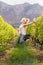 Blonde winegrower jumping in a vineyard