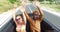 Blonde woman and black man waving arms riding in the back seat of convertible