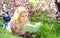 Blonde Woman with Book under Cherry Blossom