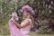 Blonde woman enjoying in a spring garden with blooming lilacs with bouquet, lilac flowers hair style.