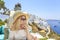 Blonde woman enjoying the view of greek town Thira in Santorini, Greece
