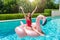 Blonde woman enjoys a hot summer day in the pool with a giant floatable flamingo