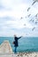 Blonde woman feeding seagulls in cloudy autumn day