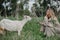 Blonde woman feeds goat on meadow