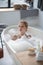 Blonde woman feeling amazing relaxing in bath with foam