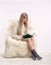 Blonde woman on furry arm-chair with book in hands