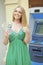 Blonde woman in a green dress is holding a cash dollars