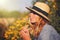 Blonde woman in hat blowing dandelion at summer