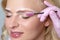 Blonde woman having permanent make-up tattoo on her eyebrows. Closeup beautician doing tattooing eyebrow.Professional makeup and