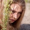 Blonde woman hiding behind plant