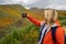 Blonde woman hiker takes a selfie with a cell phone while at Walker Canyon, enjoying the California Poppies superbloom