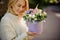 Blonde woman holds round lilac box with flower arrangement inside it