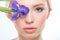 Blonde woman with iris flower on eye looking at camera, skincare concept