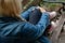 Blonde woman in jeans jacket sitting alone on a park bench, holding her leg