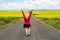 Blonde woman poses on an empty farm road with arms raised, near a field of mustard flowers in the Palouse region of Western Idaho