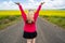 Blonde woman poses on an empty farm road with arms raised, near a field of mustard flowers in the Palouse region of Western Idaho