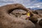 Blonde woman poses in front of Moibus Arch in the Alabama Hills of California in the SIerra