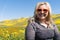 Blonde woman poses with wildflower field at Carrizo Plain National Monument in California. Wearing orange sunglasses