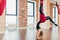 Blonde woman practices inversion anti-gravity yoga position, hanging upside down