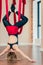 Blonde woman practices inversion anti-gravity yoga position, hanging upside down