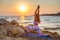 Blonde woman practicing yoga on the beach during sunset