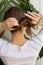 Blonde woman in the process of making sleek low bun.