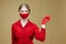 Blonde woman in red gloves and a mask points the direction with her index finger. the concept of prevention of the covid 19