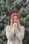 Blonde woman in red knitted hat against of fir trees