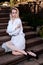 Blonde woman sits on the steps of the old granite stair. Young woman modern portrait