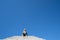 Blonde woman sits on top of concrete stairs platform against a blue sky. Negative space composition, with lots of copyspace for