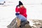 Blonde woman sitting on a rock in the snowy mountains in winter, in Sierra Nevada, Granada, Spain.