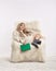 Blonde woman is sleeping in furry arm-chair with book in hands