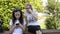 Blonde woman spies on a brunette girl while she is using her smartphone