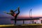 Blonde woman standing in front of a lake doing yoga exercises during sunset