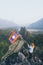 Blonde woman stands on the mountain peak with Laotian flag in her hands overlooking the valley in Vang Vieng, Laos