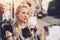 Blonde woman in street cafe with cup of tea