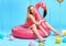 Blonde woman in stylish casual clothes sitting on inflatable flamingo