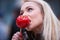 Blonde woman tasting a red apple candy