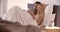 Blonde woman using smartphone with boyfriend in bed at morning. Couple in love morning wake up at home in bedroom