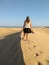 blonde woman walking at the top of a dune while looking the sea on the horizon at the sunset. Walking the barefoot girl is shaping