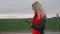 Blonde woman walks on the road and using the smartphone. Girl with a red scarf look at the phone