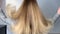 Blonde woman waving her beautiful, healthy hair after a treatment at a beauty salon.