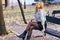 Blonde woman wearing denim shirt and black leather skirt sitting in an urban bench.